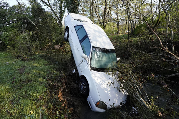 A car that was carried by floodwaters leans against a tree in a creek in Nashville, Tenn., on Sunday. Heavy rainfall flooded roads, submerged vehicles and left many people in need of rescue.