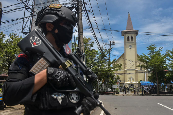 A police officer stands guard outside the Sacred Heart of Jesus Cathedral in Makassar, Indonesia, on Sunday. Two suicide bombers attacked the Roman Catholic compound, injuring at least 20 people.