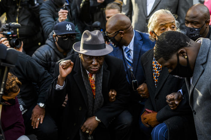 Attorney Ben Crump (center) took a knee with members of George Floyd's family and Rev. Al Sharpton for 8 minutes and 46 seconds outside the Hennepin County Government Center in Minneapolis, Minn., on Monday, shortly before opening arguments began in the trial of former police officer Derek Chauvin.