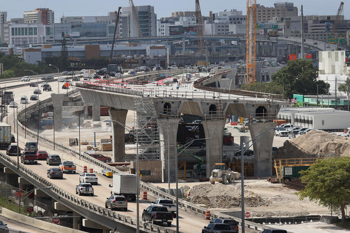 Workers improve a busy highway intersection in Miami. President Biden is proposing roughly $2 trillion to invest in the nation's infrastructure. His plan includes improvements for roads, bridges, transit, water systems, electric grids and Internet access.