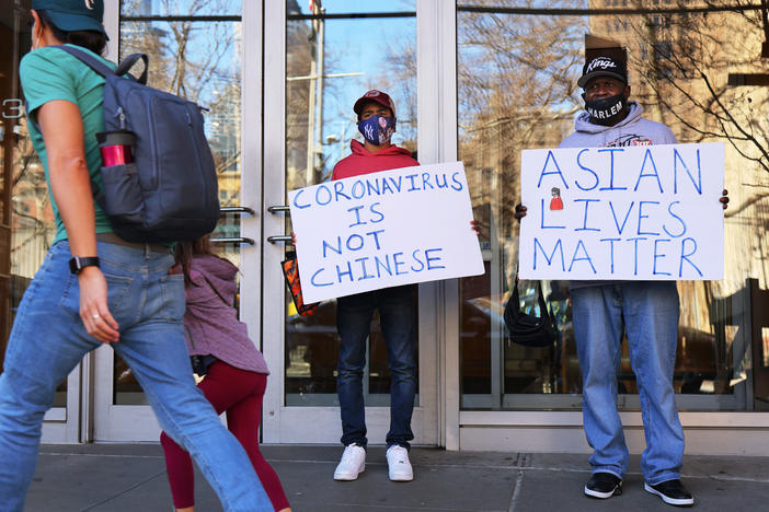 Cameron Hunt and his father, Calvin Hunt, hold signs of support on Tuesday outside the West 43rd Street apartment building in Manhattan where a man physically and verbally attacked a 65-year-old Asian American woman on Monday in an incident that police are investigating as a hate crime.