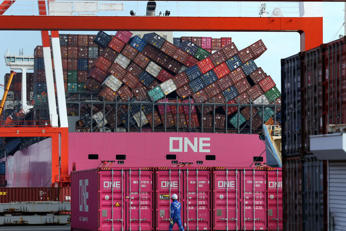 A worker walks past the ONE Apus container ship and its dislodged containers at the Kobe Port in Japan in December. The vessel suffered a massive stack collapse and lost 1,816 containers at sea during severe weather on Nov. 30.