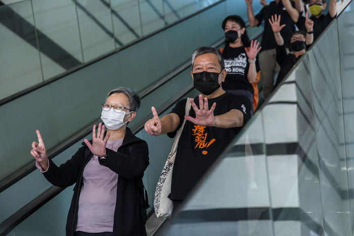 Former lawmaker Cyd Ho (left) and pro-democracy activist Lee Cheuk-yan (center) gesture a protest slogan, "Five demands, not one less," as they leave West Kowloon court in Hong Kong on Thursday after being found guilty of organizing an unauthorized assembly.