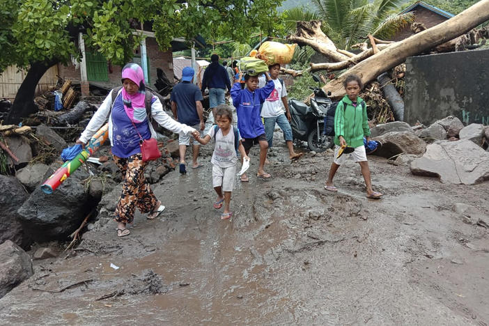 People walk amid debris Sunday in a village affected by flooding in Ile Ape on Lembata Island in Indonesia's East Nusa Tenggara province.