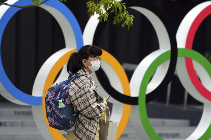 A woman wearing a protective mask to help curb the spread of the coronavirus walks in front of he Olympic Rings on Tuesday in Tokyo. North Korea says it will not attend the games over COVID-19 fears.