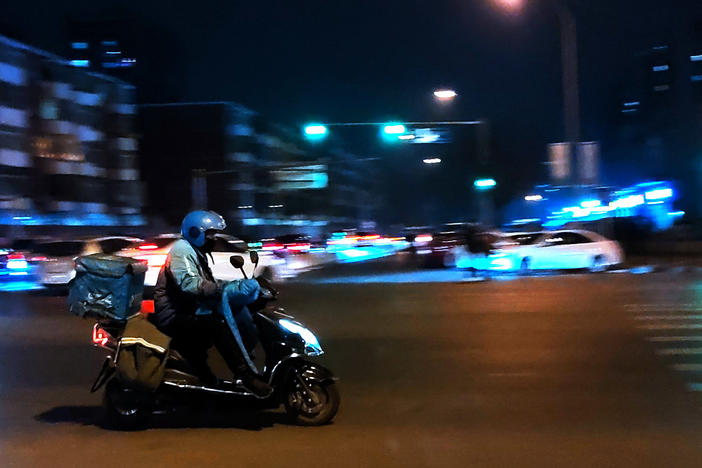 A courier delivers goods at night on a street in Beijing in February.