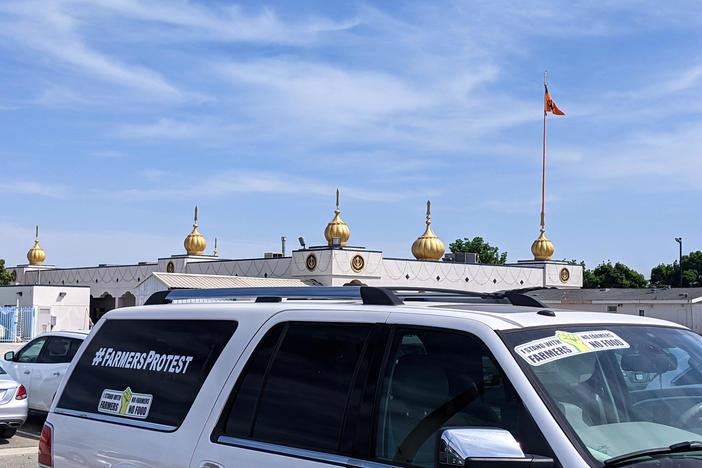 A car parked in a Fresno Gurdwara, or Sikh temple, parking lot with a bumper sticker showing support for Indian farmers protesting new agricultural laws.
