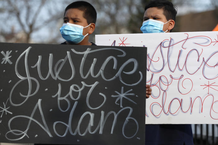 Two boys hold signs at an April 6 news conference, days after a Chicago police officer fatally shot 13-year-old Adam Toledo.