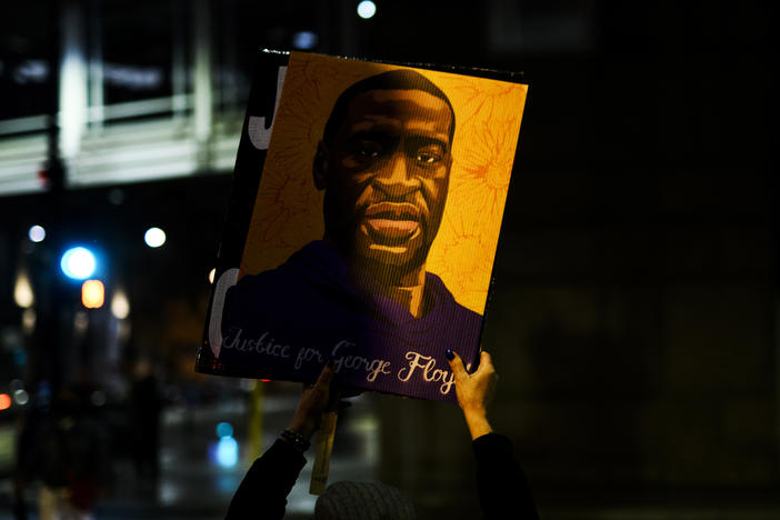 A person holds up a portrait of George Floyd as people gather outside the Hennepin County Government Center on April 9 in Minneapolis