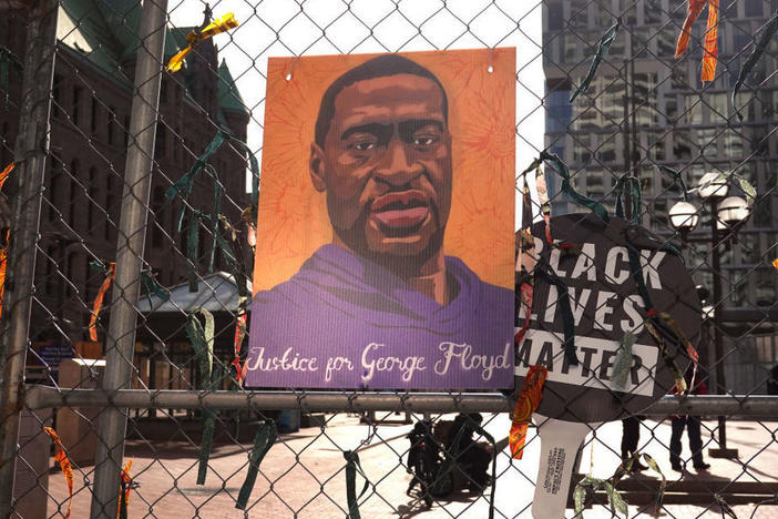 A picture of George Floyd hangs on a fence barrier that surrounds the Hennepin County Government Center in Minneapolis during the trial of former police officer Derek Chauvin in March. The Justice Department is now bringing criminal charges against Chauvin over allegedly violating Floyd's rights and using excessive force in restraining him.