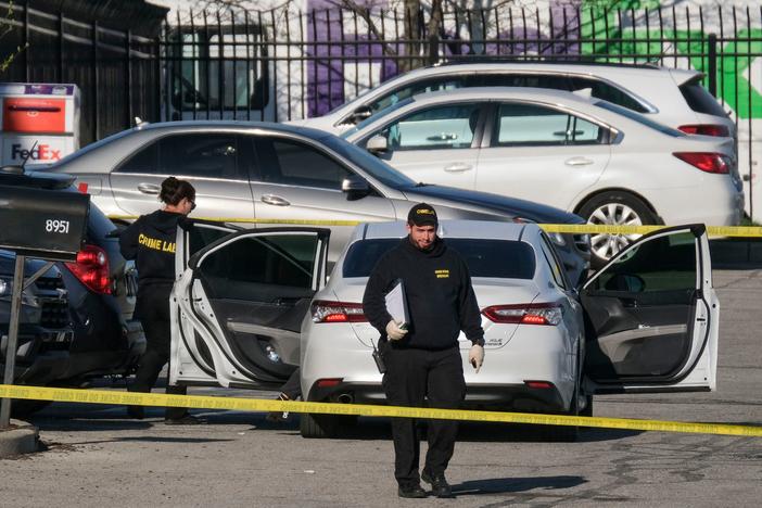 Crime scene investigators walk through the parking lot of a FedEx facility in Indianapolis on Friday. A gunman killed at least eight people and injured several others.