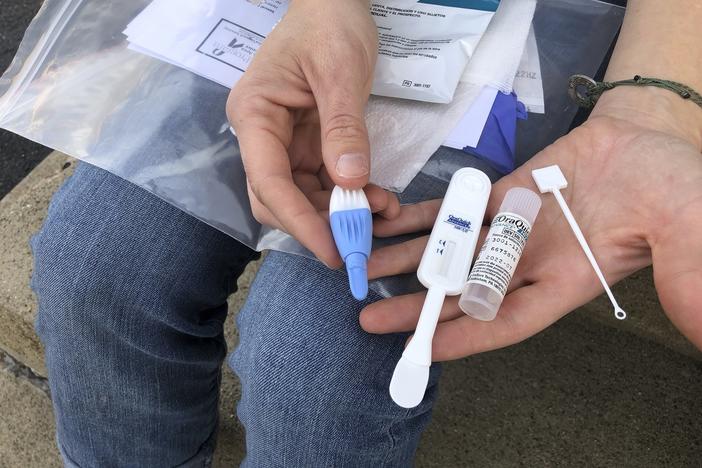 Brooke Parker, an organizer with the group Solutions Oriented Addiction Response, displays an HIV testing kit in Charleston, W.Va., in March. Outbreaks of HIV/AIDS are expected to rise as resources have been redirected to the fight against COVID-19 — delaying and sometimes cutting off HIV testing and treatment.