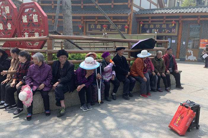 Resettled villagers sun themselves outside Qixingguan. Many older residents have had a difficult time adjusting to life away from their fields.