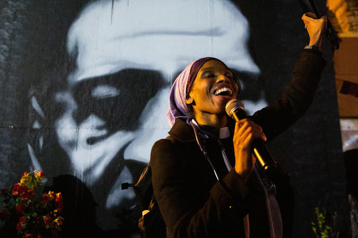 Jeanette Rupert smiles as she speaks to the crowd at George Floyd square in front of "Icon of a Revolution," a painting of Floyd by Peyton Scott Russell, in Minneapolis. Rupert grew up in the neighborhood and helped found 612 MASH, a nonprofit that provides medical treatment to people in and around George Floyd Square.