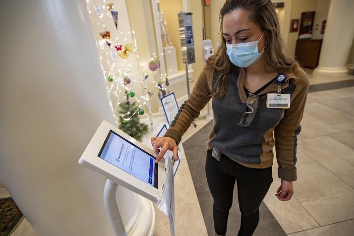 Interpreter Ana Maria Rios-Velez demonstrates the screening app at the front entrance of Brigham and Womens Hospital in Boston. It has a multilingual function to better communicate with non-English speaking patients and staff.