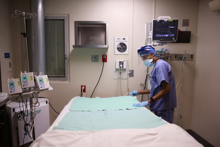 Intensive Care Unit nurse Subramanya Kirugulige prepares a bed for an arriving COVID-19 patient at Roseland Community Hospital in Chicago in December. A large study has found that people with severe initial cases of COVID-19 tend to be at greater risk of more health problems later on.