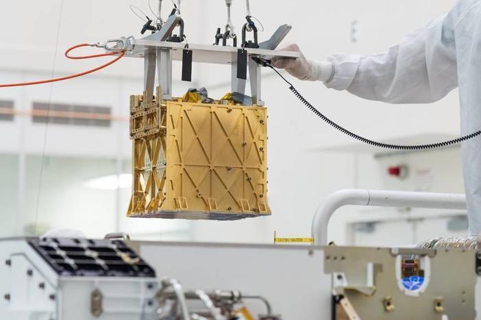 Technicians at NASA's Jet Propulsion Laboratory lower an instrument known as MOXIE, or the Mars Oxygen In-Situ Resource Utilization Experiment, into the belly of the Perseverance rover. NASA announced the instrument had produced oxygen from the Martian atmosphere.