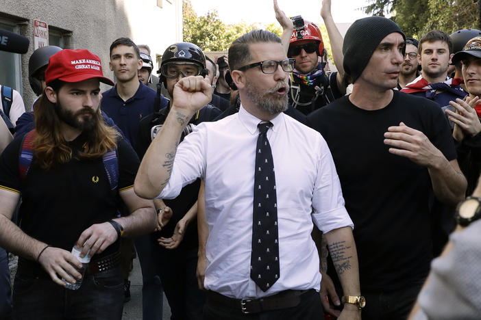 In this 2017 photo, Gavin McInnes (center), founder of the far-right extremist group known as the Proud Boys, is surrounded by supporters after speaking at a rally in Berkeley, Calif. McInnes told NPR that the group is made up of "funny dudes, not Nazis." At least 25 members of the far-right group are facing charges related to the Jan. 6 attack on the Capitol.