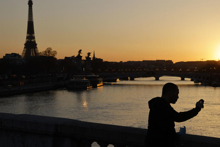 A man takes a picture at sunset with the Eiffel Tower in the background in March in Paris. The president of the European Commission says fully vaccinated Americans will be able to visit the European Union this summer.