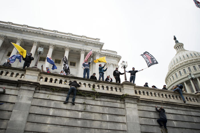 Supporters of former President Donald Trump climb the west wall of the the U.S. Capitol on Jan. 6. A New York man who was not at the riot is on trial for allegedly threatening to kill members of Congress in media posts supportive of the assault.