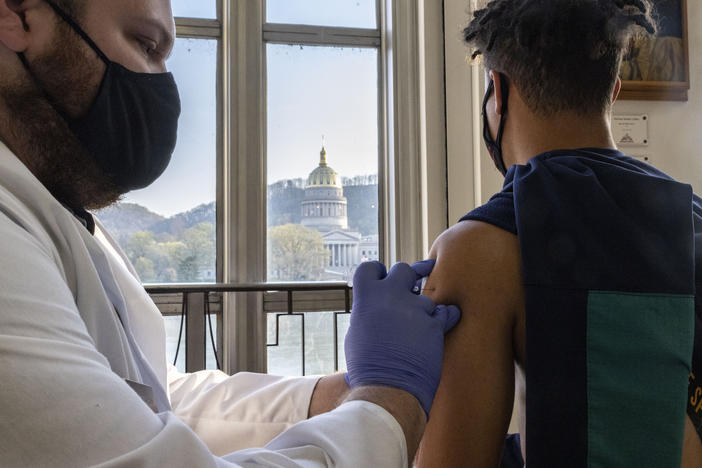 A young man receives a COVID-19 vaccine in Charleston earlier this month while overlooking the West Virginia Capitol building.