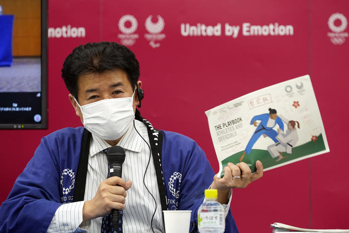 Tokyo Games Delivery Officer Hidemasa Nakamura holds a sample of an updated version of the playbook during a news briefing on Wednesday.