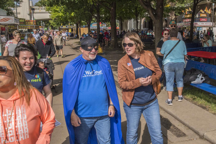 Minnesota's state demographer, Susan Brower (center), walks with Dean Goldberg, donning a blue cape and black mask as "Census Man," through the 2019 Minnesota State Fair in St. Paul, Minn., to encourage residents to participate in the national head count.