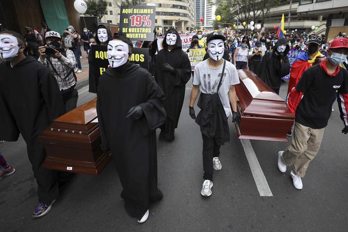 Protesters wearing Guy Fawkes masks carry empty coffins during a national strike to protest a government proposal that would raise taxes, in Bogotá, Colombia, on Wednesday.