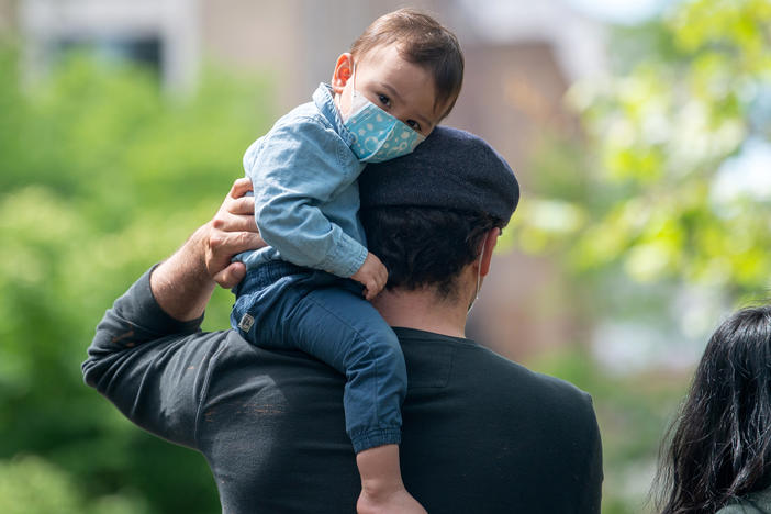 A child sits on his father's shoulder in New York City's Central Park in May 2020. The COVID-19 vaccine isn't presently available to those under 16, raising questions for parents and their kids.