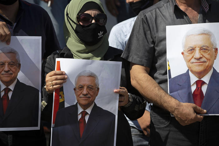 Palestinians wearing protective face masks amid the coronavirus pandemic hold pictures of Palestinian Authority President Mahmoud Abbas during a September rally in the West Bank town of Tubas.