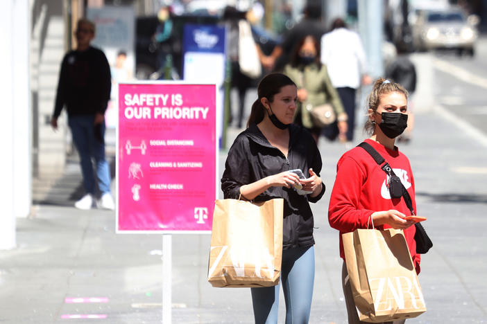 Pedestrians carry shopping bags as they walk through the Union Square shopping district on April 15 in San Francisco. Data on Friday showed personal income jumped 21.1% last month, in what was the largest increase on record.