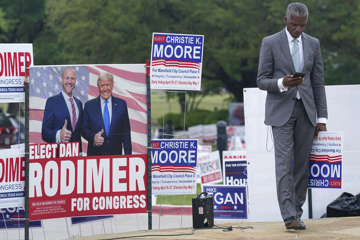 Volunteer Al Green looks at his phone as he takes a break from holding a sign supporting his candidate in a local election outside an early voting location Tuesday, April 27, 2021, in Mansfield, Texas.