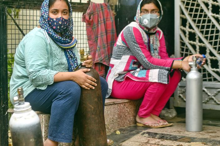 India has reported more than 20 million coronavirus cases, adding more than 2.6 million new cases in the past week alone. Here, women wait to refill empty oxygen cylinders in New Delhi. Oxygen shortages are blamed for deaths at even the best-equipped urban hospitals in India.