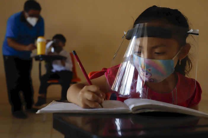 Wearing a mask and a face shield to curb the spread of the coronavirus, 10-year-old Jade Chan Puc writes in her workbook during the first day of class in Hecelchakán, Campeche state, Mexico, on April 19. On average, schools in Latin America and the Caribbean were closed longer than any in any other region, according to UNICEF.