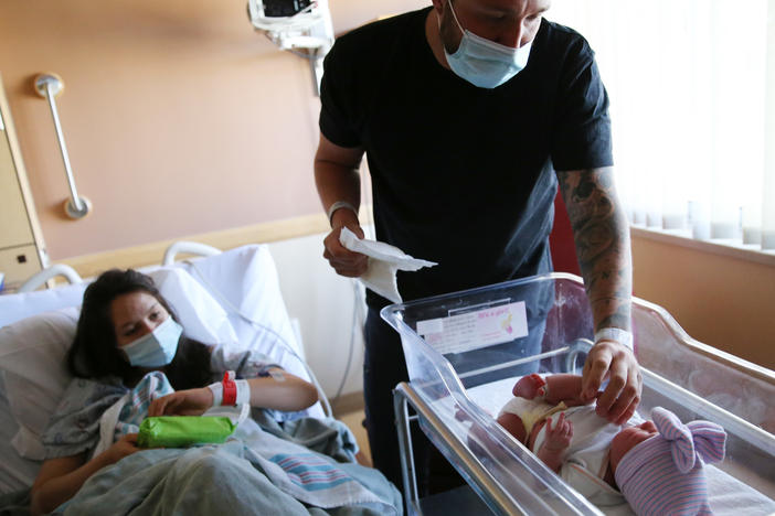 Matthew Carnes prepares to change diapers for his newborn daughter, Evelina Carnes, as his wife, Breanna Llamas, keeps watch in the postpartum unit at Providence St. Mary Medical Center in Apple Valley, Calif., in March. The U.S. has reported another record low in its birthrate.