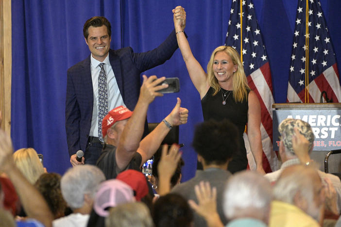 Rep. Matt Gaetz, R-Fla., and Rep. Marjorie Taylor Greene, R-Ga., raise their arms after addressing attendees of a rally Friday at The Villages in Florida.