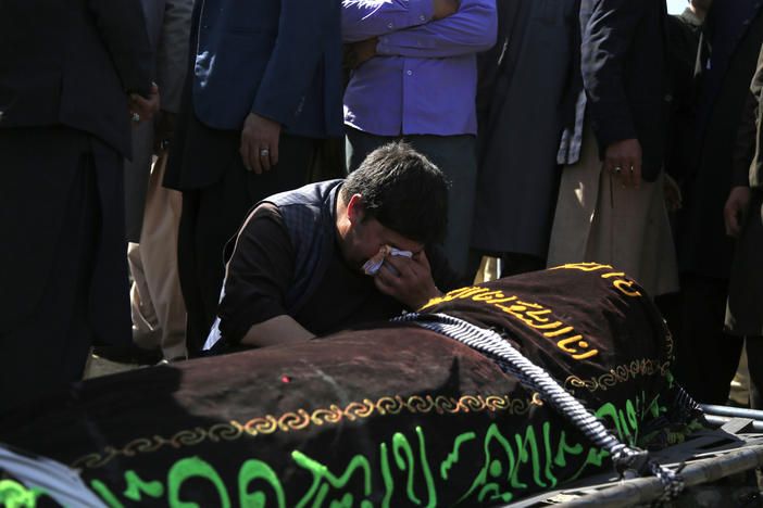 A man cries over the body of a victim of deadly bombings on Saturday near a school, at a cemetery west of Kabul on Sunday. More than 50 were killed in the attack, many of them pupils between 11 and 15 years old. More than 100 were wounded.