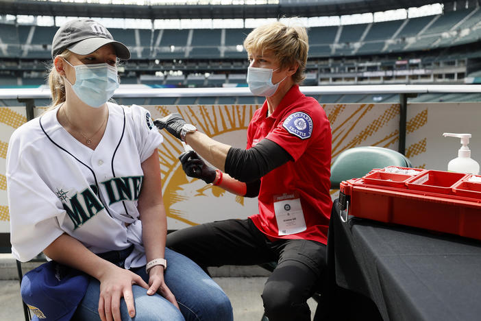 Sydney Porter of Bellevue, Wash., receives her COVID-19 vaccination from Kristine Gill, with the Seattle Fire Department's Mobile Vaccination Teams, before the game between the Seattle Mariners and the Baltimore Orioles at T-Mobile Park on May 5 in Seattle. A late spring COVID-19 surge has filled hospitals in the metro areas around Seattle.