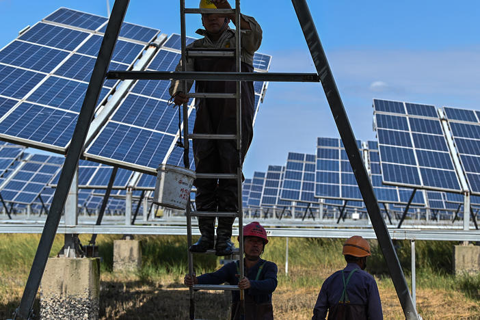 Workers next to solar panels in an integrated power station in Yancheng, China, in October. An unprecedented amount of renewable power came online in the fourth quarter of 2020, according to a new report from the International Energy Agency. China alone added more than 92 gigawatts of capacity, more than triple the amount it added in the fourth quarter of 2019.