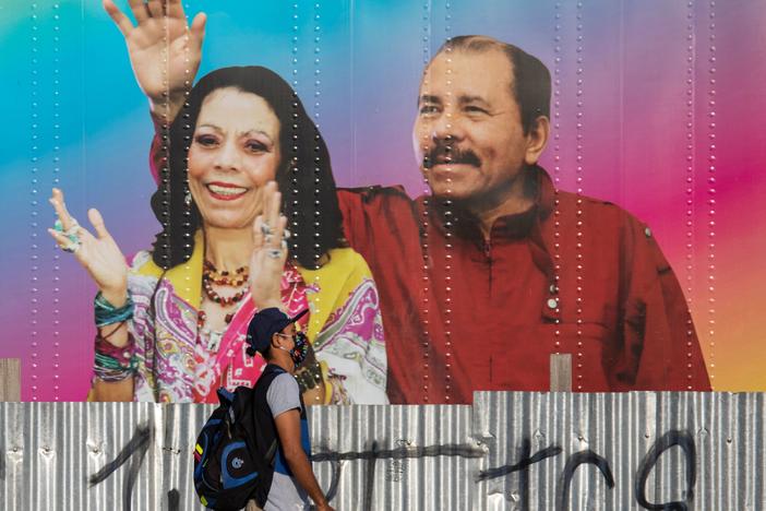 A man walks by a mobile health clinic displaying a picture of Nicaraguan President Daniel Ortega (right) and his wife and vice president, Rosario Murillo, in Managua on April 14, 2020. The government claims to be successfully combating the pandemic but health workers and critics say the toll is likely higher.