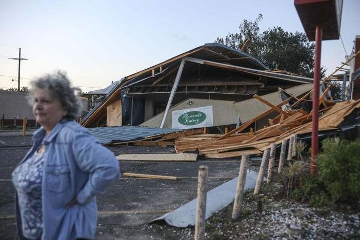 A woman stands in front of a destroyed restaurant after Hurricane Zeta on Oct. 29, 2020, in Chalmette, La. In a postseason analysis, NOAA upgraded Zeta's windspeeds, saying it was a "major" Category 3 storm when it hit.