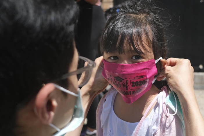 A girl in Jersey City wears a mask at her Pre-K graduation ceremony almost a year ago. Now schools are deciding how looser CDC guidelines on masks affect education.