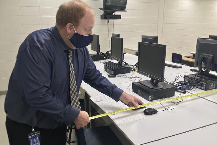 Gaylord High School principal Chris Hodges measures the space between seats in a yearbook class. A student in the class tested positive for covid, and Hodges is working with the local health department to trace people who might have been exposed to her at school.