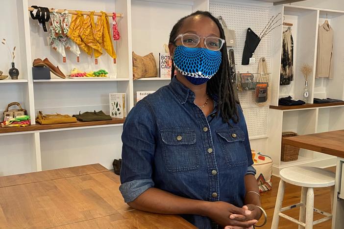 Nicole McGrew, wearing a mask by the designer N'omose Couture, says she'll require customers to mask up in her store for a short time longer.