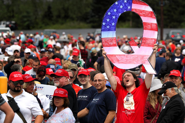 David Reinert holds up a large "Q" sign that represents QAnon while waiting in line to see then-President Donald Trump at his rally in Wilkes-Barre, Pa., on Aug. 2, 2018.