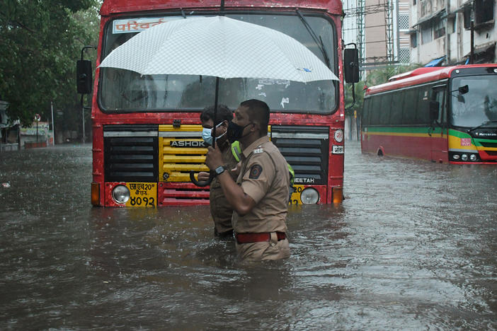 A police officer helps a public transport driver cross a flooded street caused by heavy rain from Cyclone Tauktae in Mumbai.