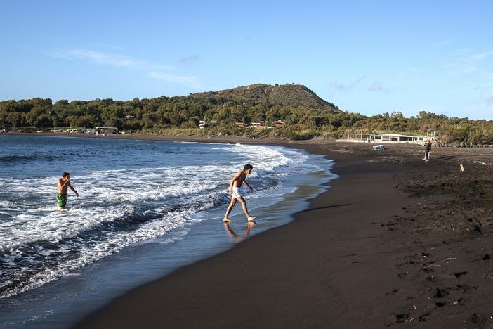 The European Union is poised to open travel to more visitors after ambassadors approved changes to travel restrictions Wednesday. Here, people walk out of the sea last week on Italy's volcanic island of Vulcano.
