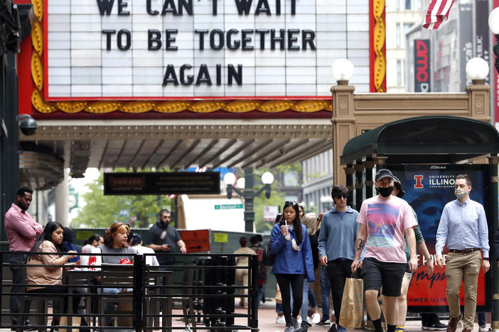 People walk near the Chicago Theatre on Tuesday in the city's Loop community. The Centers for Disease Control and Prevention eased its guidelines on the wearing of masks, saying fully vaccinated Americans don't need to cover their faces anymore in most settings. Will it encourage the unvaccinated to get their shots?