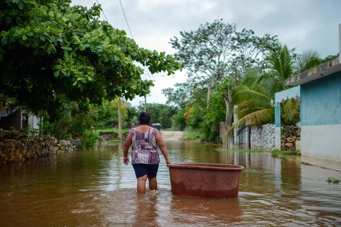 A woman from the Mayan community of Tecoh wades through the water in a flood caused by Tropical Storm Cristobal in the town of Tecoh, near Merida in Yucatan State, Mexico, in June 2020.