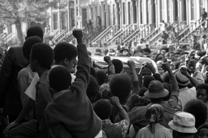 On a Brooklyn street in September 1971, a sea of fists greets the caskets of several of the incarcerated men killed in the violent clash at Attica Correctional Facility that month.